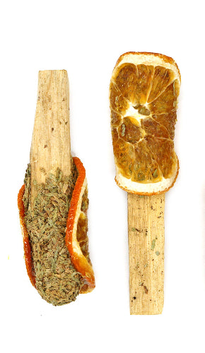 Three wooden spoons with dried orange slices and green substance on a white background